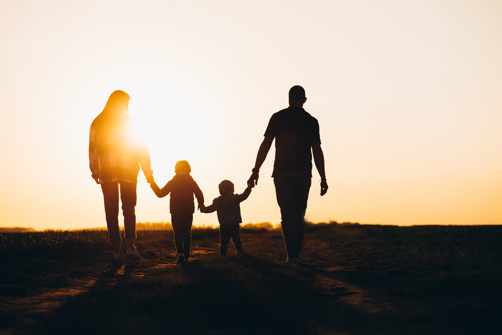 Una familia caminando tomada de la mano al atardecer